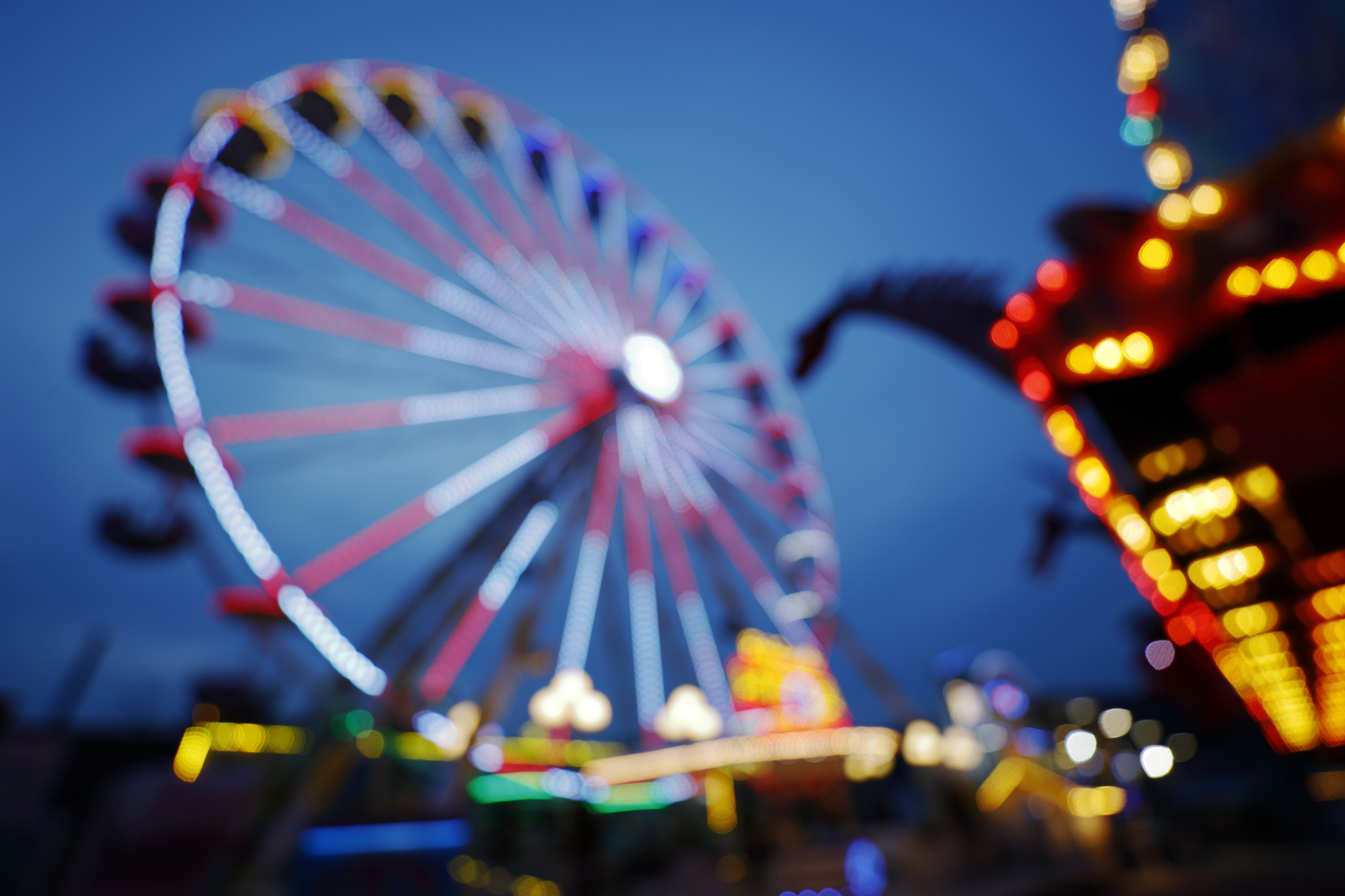 A blurry image of a ferris wheel and other carnival rides
