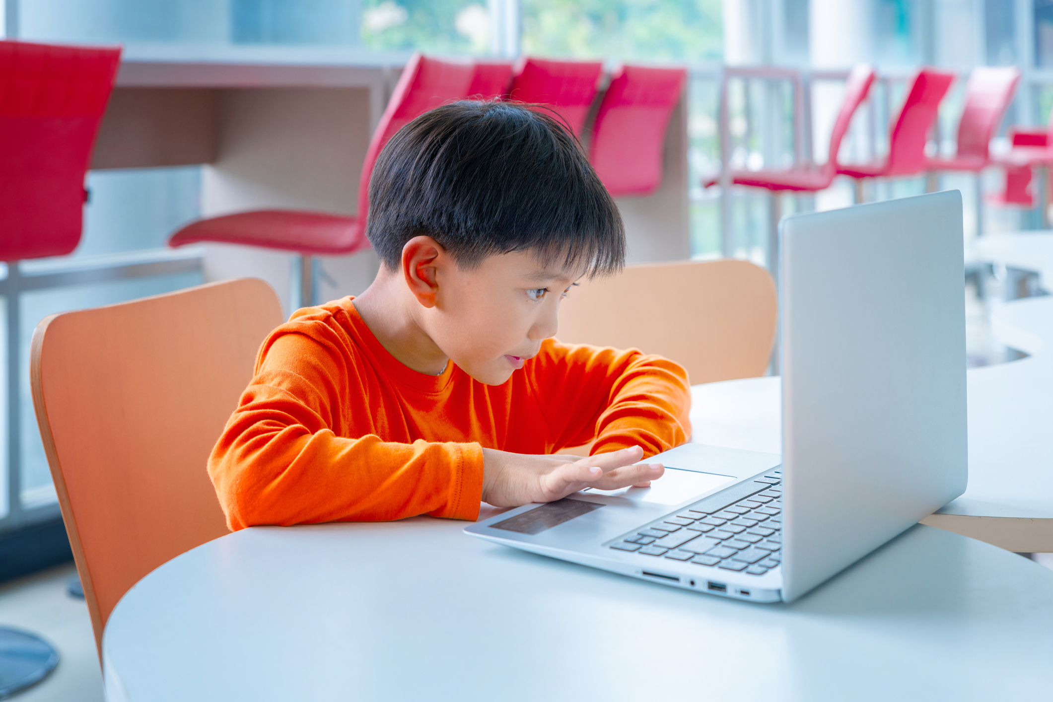 A boy sits at a desk in front of a computer
