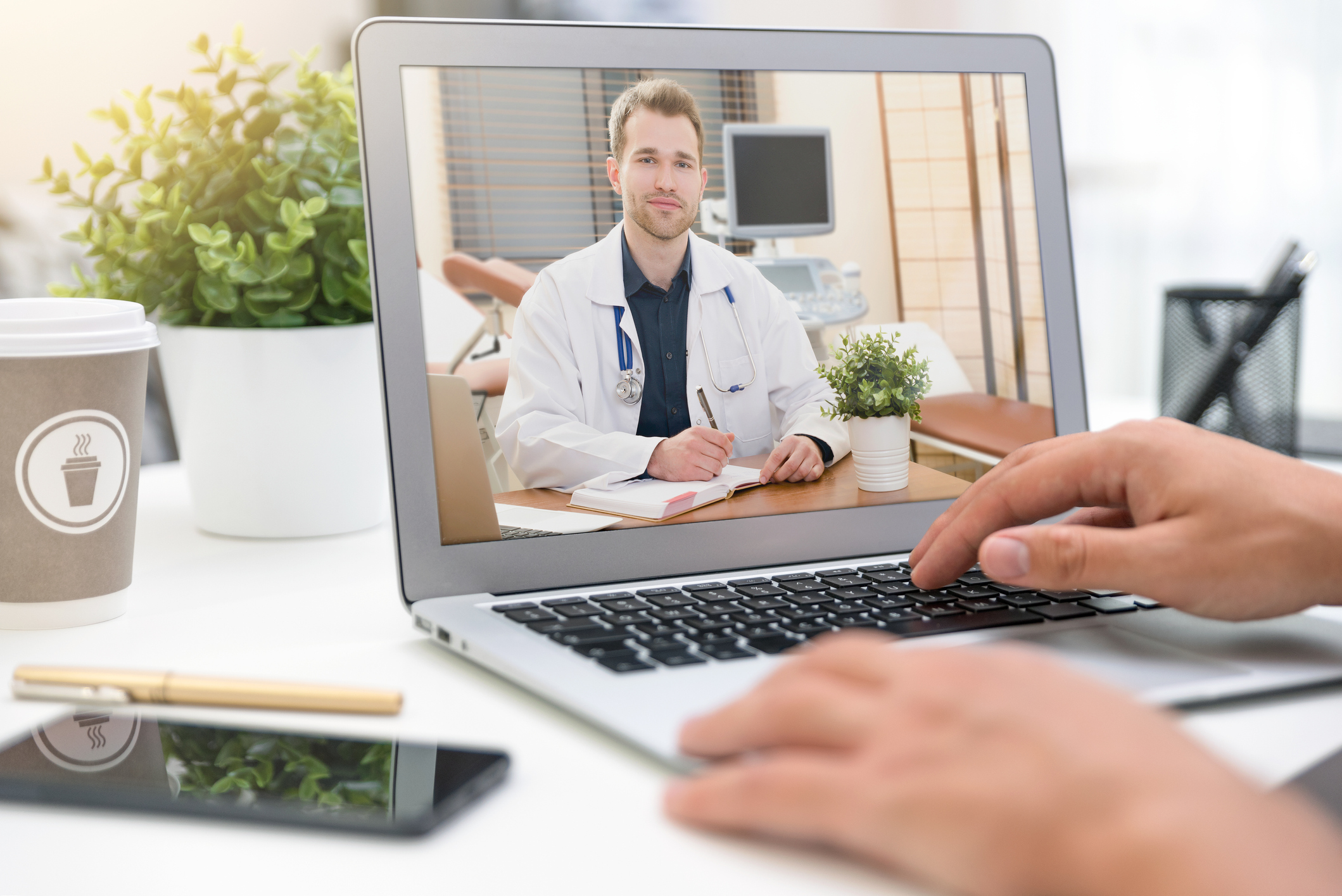 A person speaking to a doctor via a video conference app on a laptop.