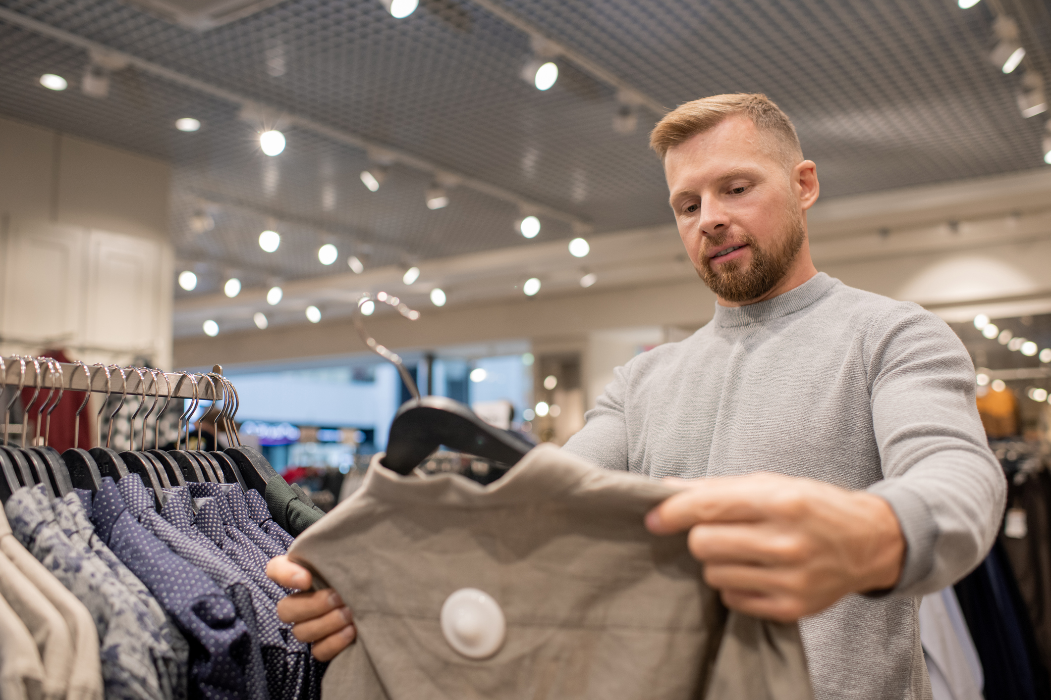 A man looking at a sweatshirt on a hanger in a retail store