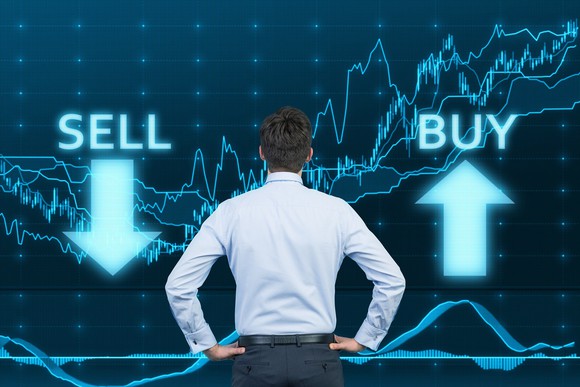 Man looking at graphic with buy and sell on each side of it.