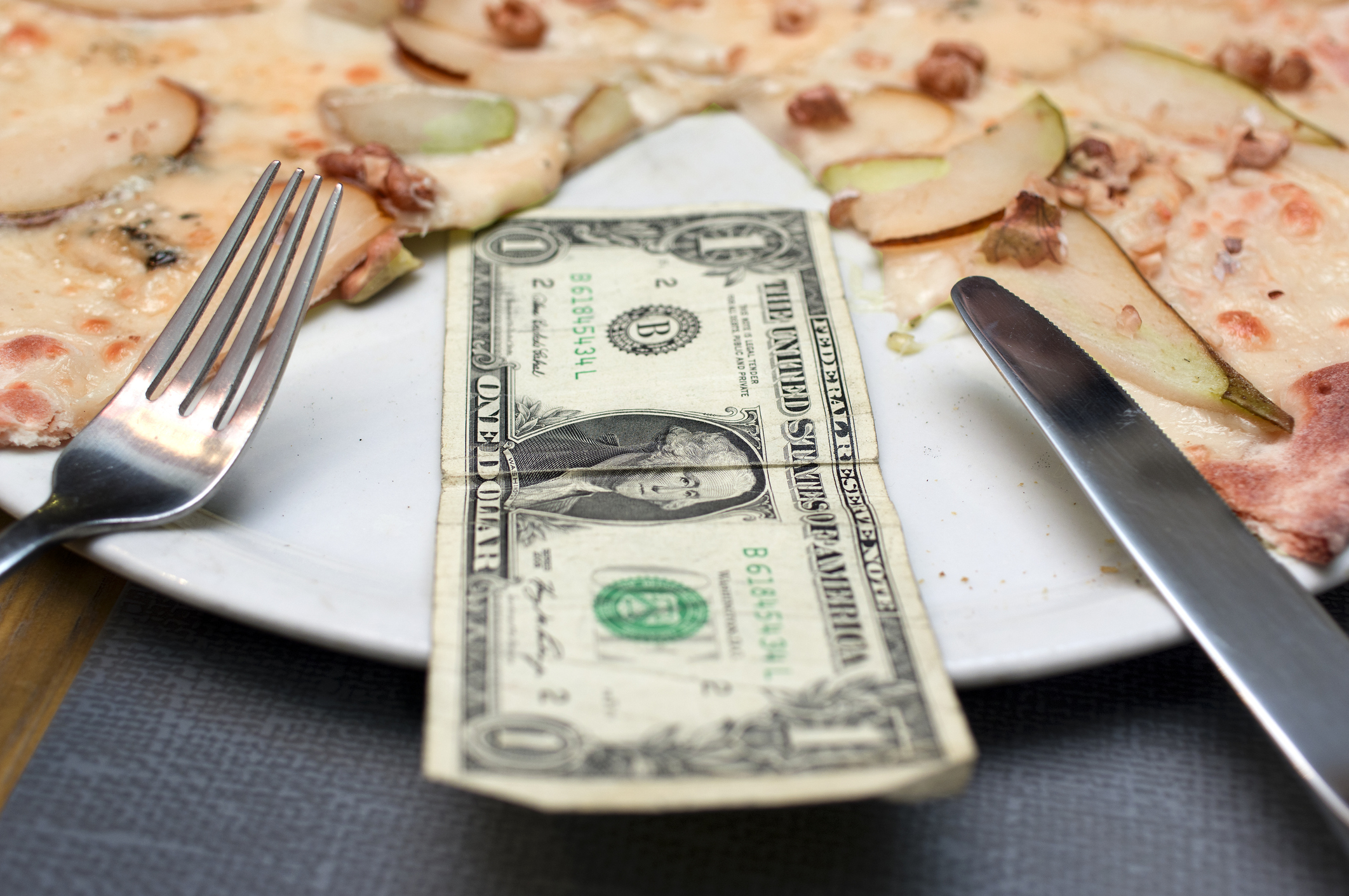 Pizza pie with a one-dollar bill in place of one slice.