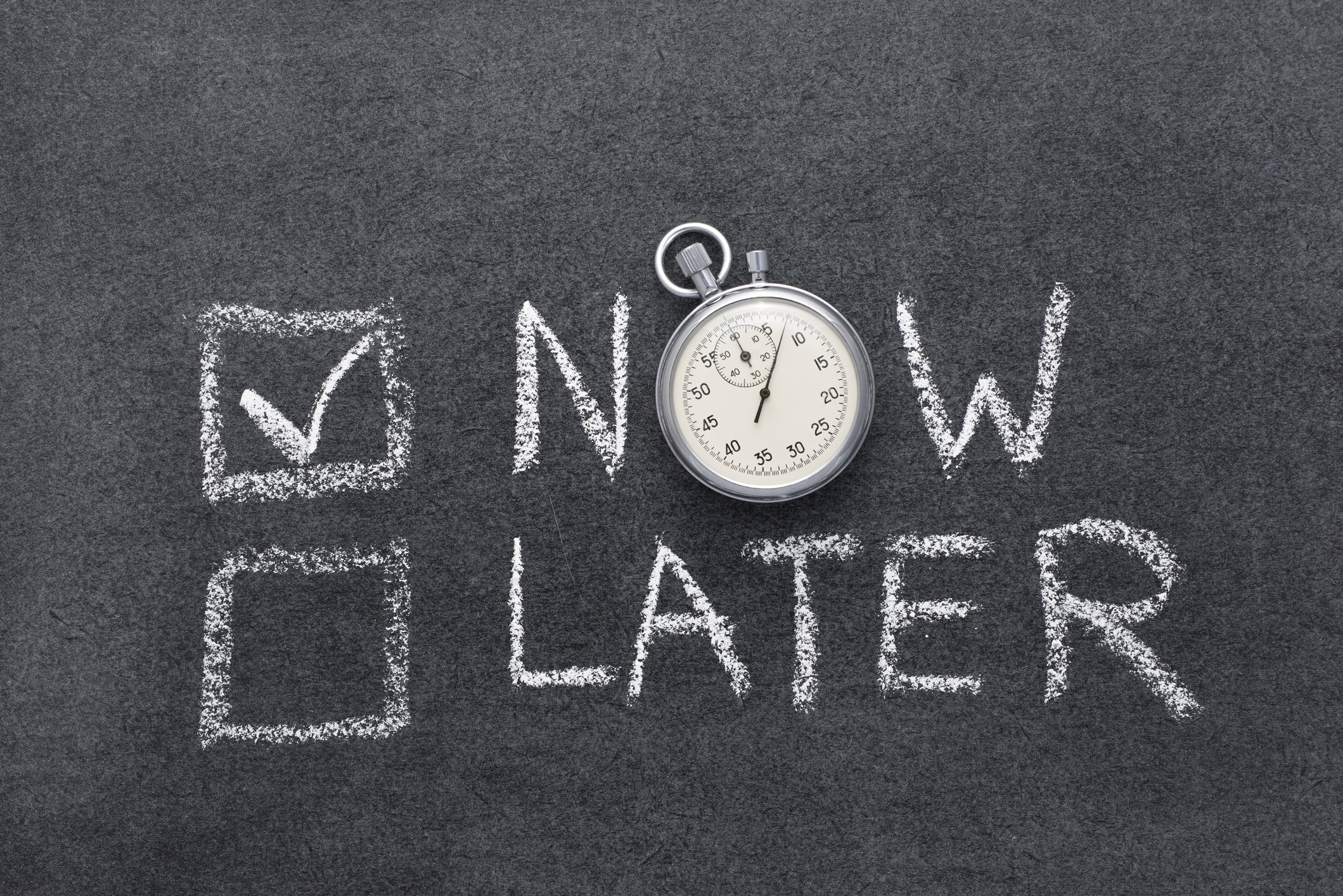 Now and Later written on a chalkboard with the Now box checked and a stop watch replacing the letter O.