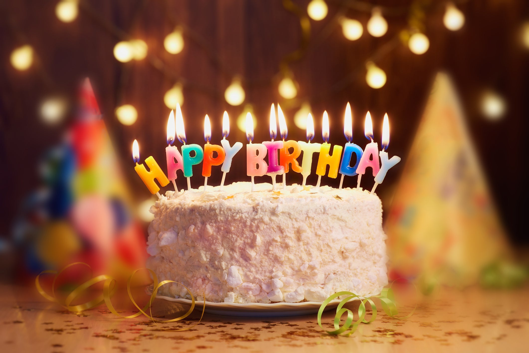 A birthday cake with candles spelling out HAPPY BIRTHDAY.