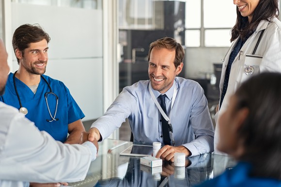 Salesman shaking hands with doctor in a conference.