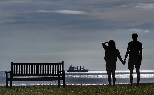 Couple holding hands looking out at a horizon.