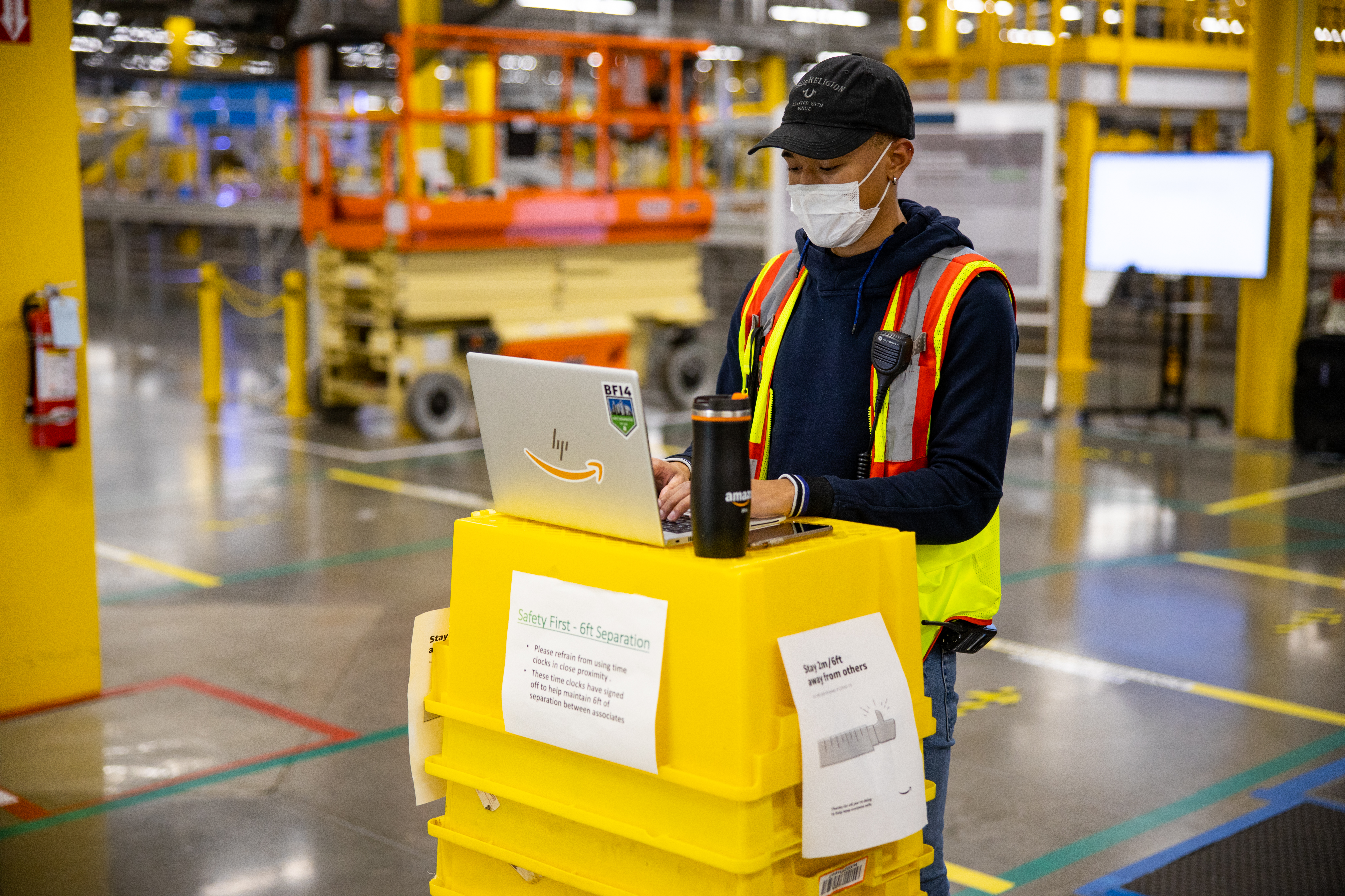 Amazon worker typing on a laptop and wearing PPE 