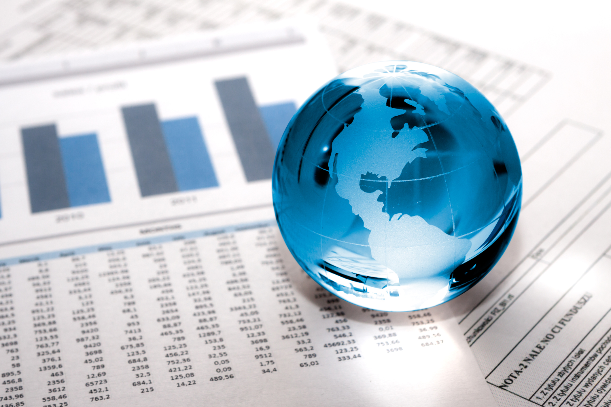 A globe marble resting atop some financial papers