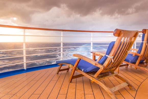 A pair of deck chairs overlooking the ocean a cruise ship railing.