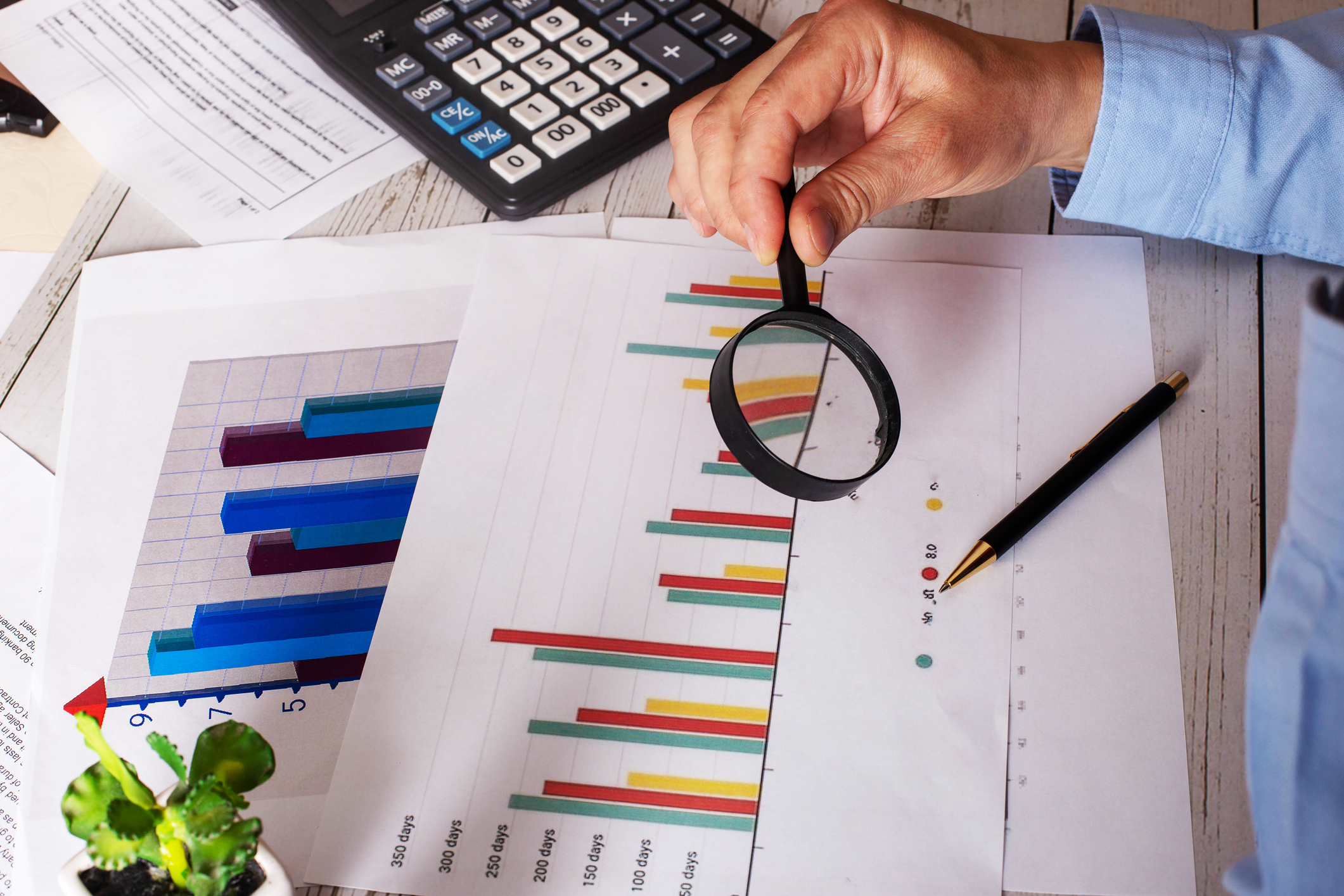 A businessman examines a financial chart with a magnifying glass.