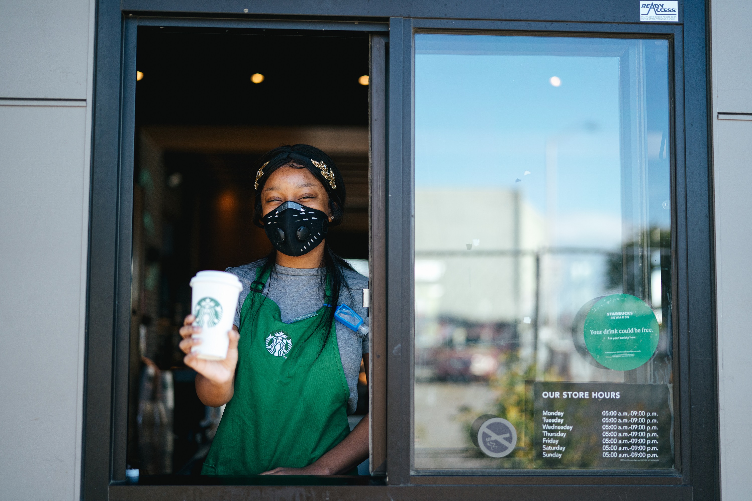 Starbucks barista wearing a mask at the drive-in window.