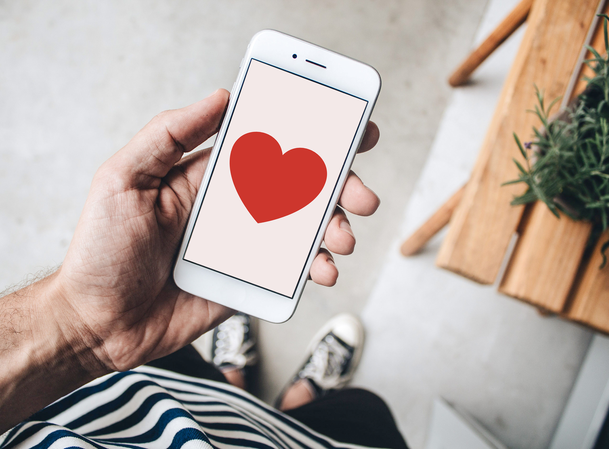 A person holding a mobile phone displaying a heart.