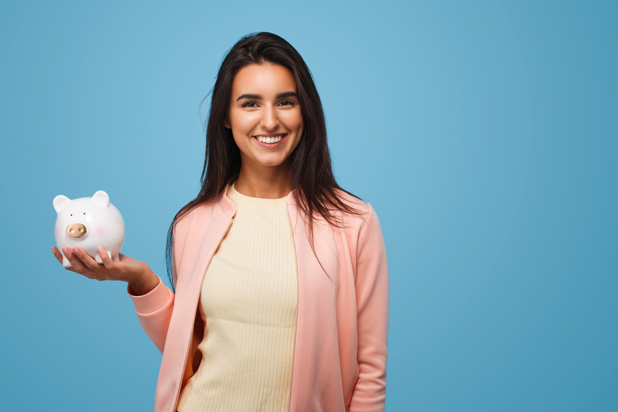 Young smiling woman holding piggy bank