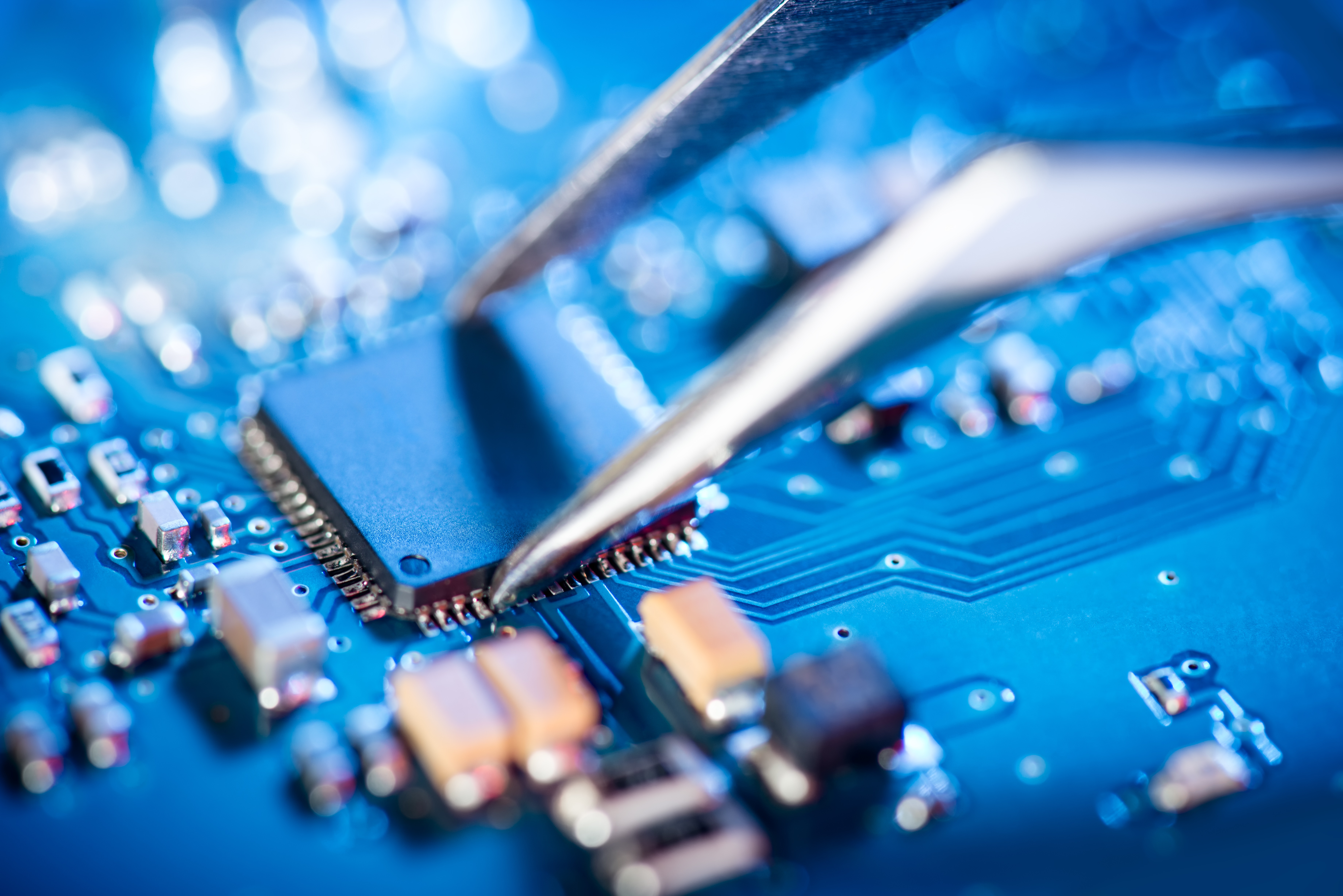 A semiconductor being placed on a blue circuit board.