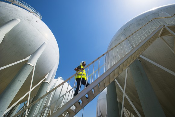 A man walking up a stairwell between multiple liquified petroleum gas storage tanks