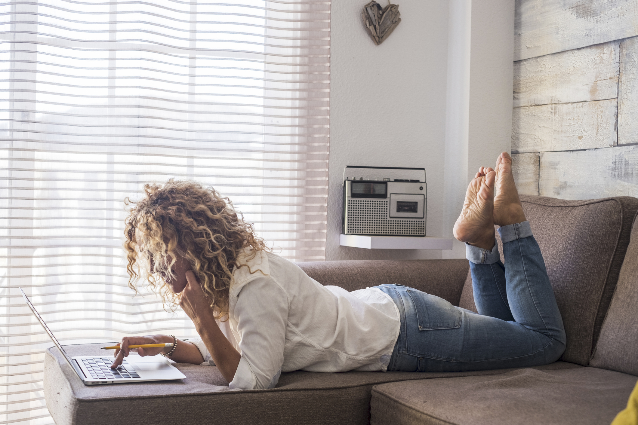 Woman lying on her sofa while using her laptop.