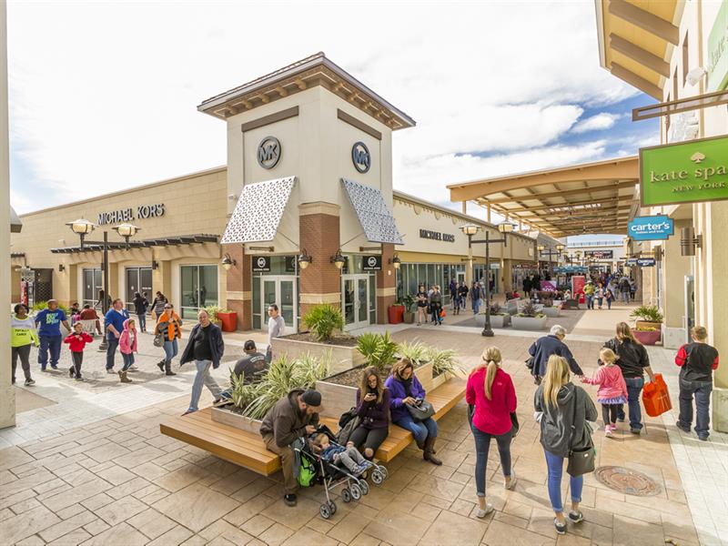 A Tanger outlet center in Fort Worth with several shoppers walking around.