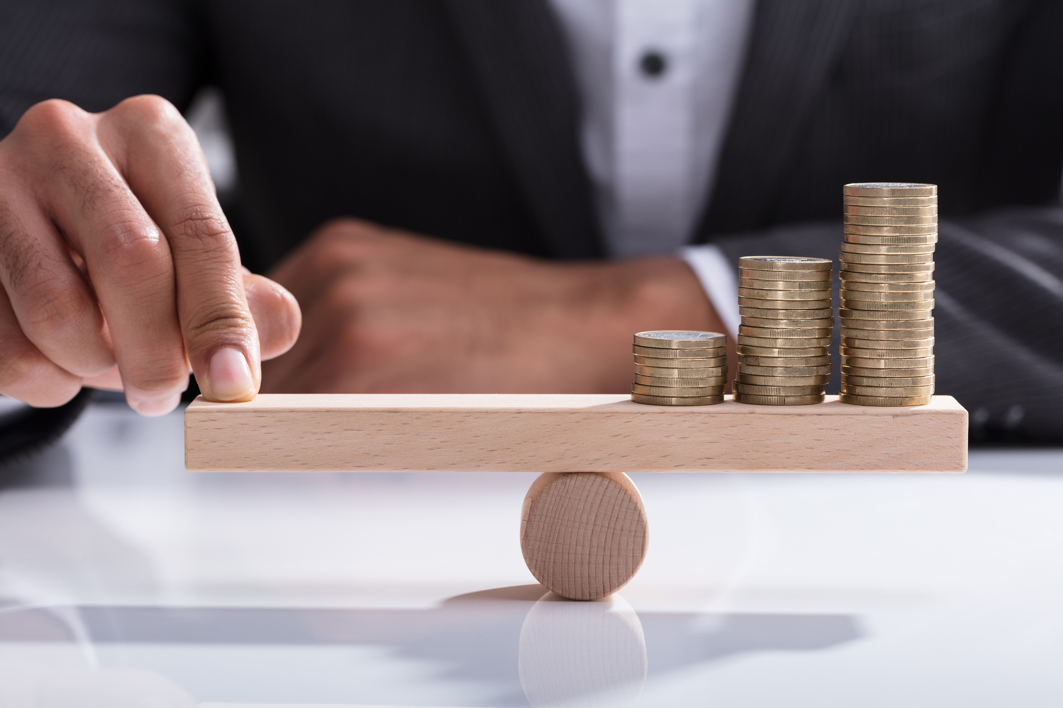 19_07_18 A man holding one side of a balance beam with his finger offsetting coins on the other side _GettyImages-917884914