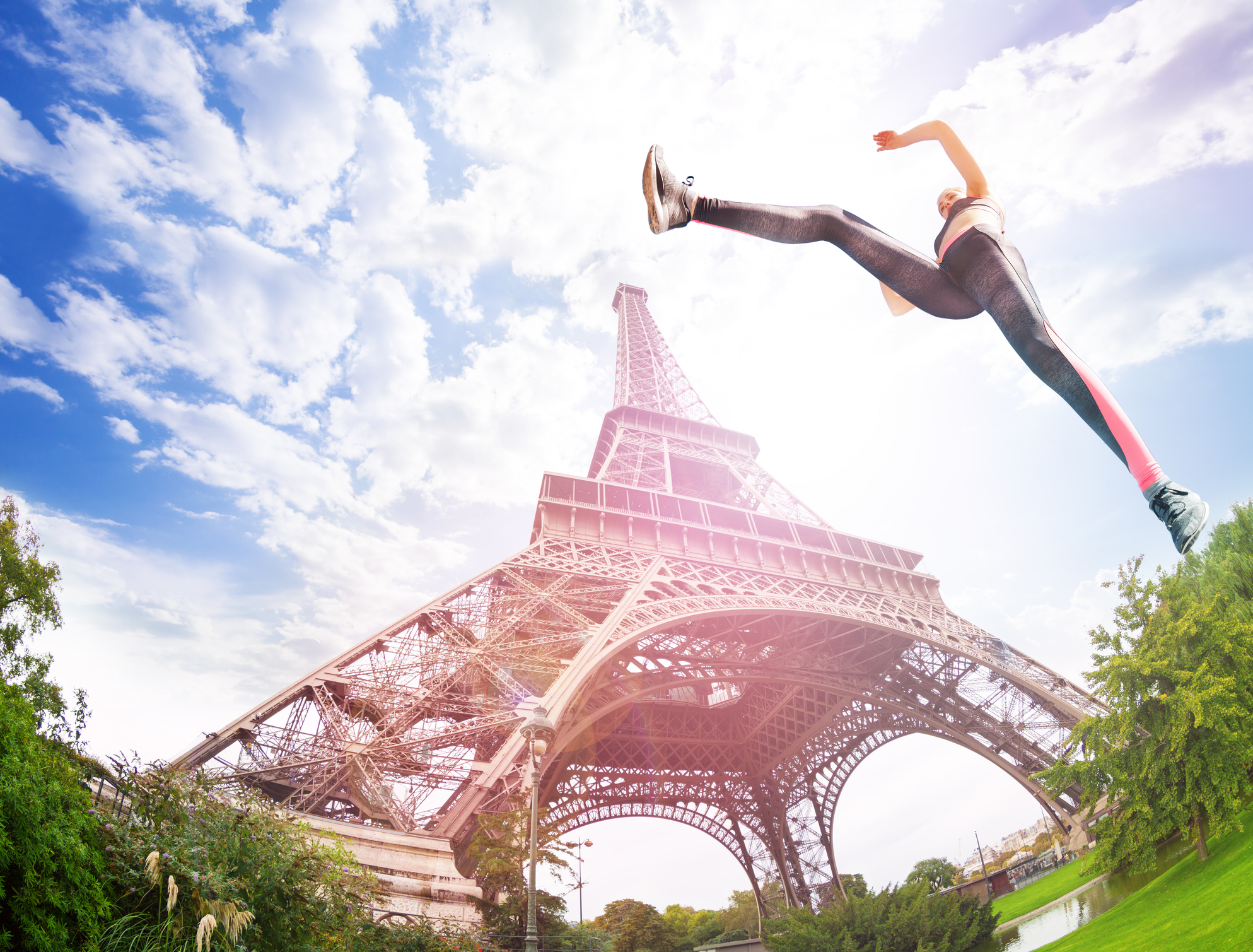 A woman jumping in the air with the Eiffel tower in the background.