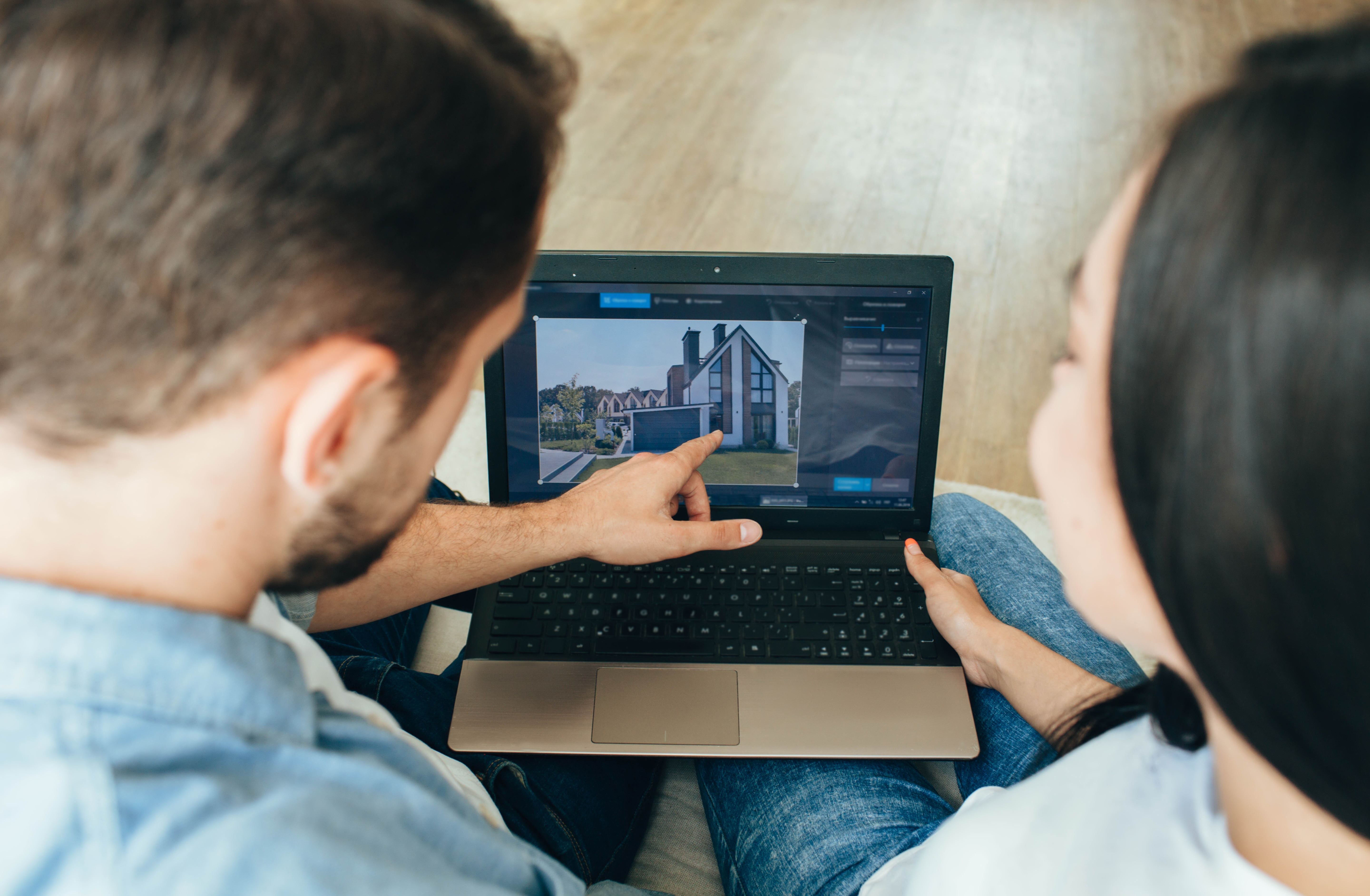 A couple at home shopping for real estate  on a laptop.
