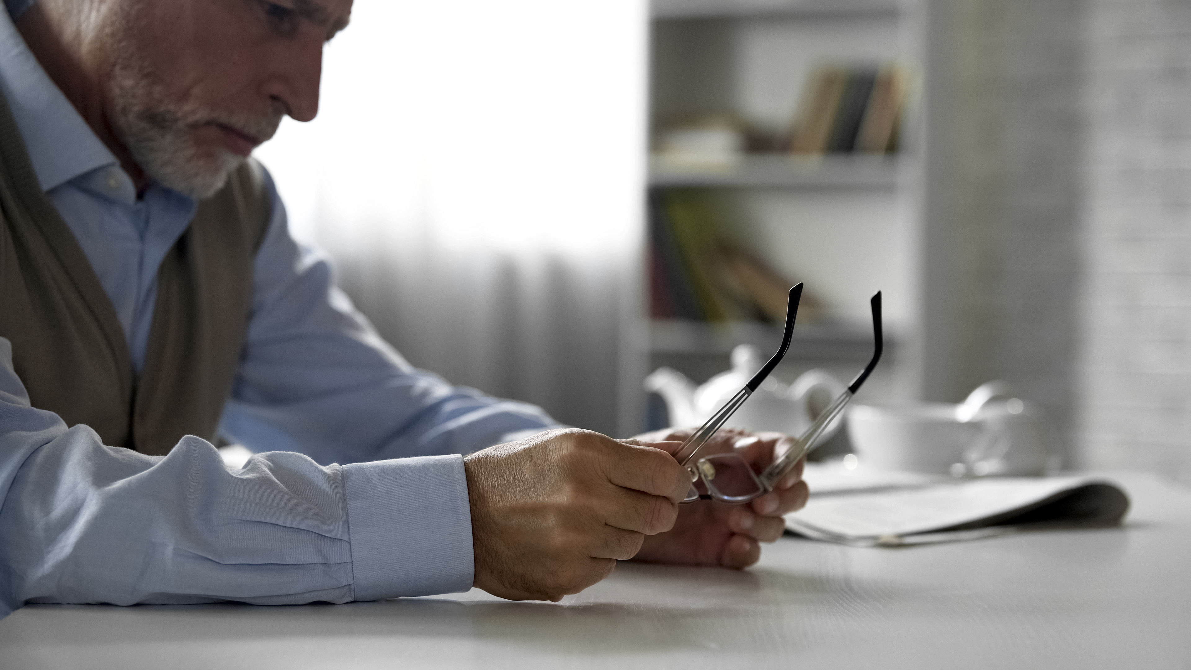 Older man holding eyeglasses