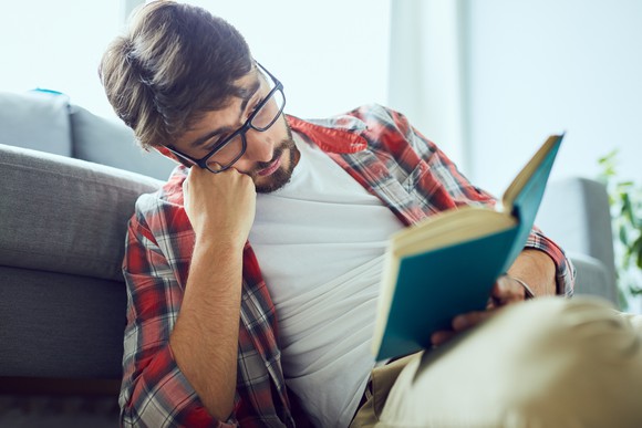 Man sitting on floor reading book