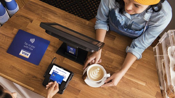 Overhead view of a person buying coffee at a cafe with a Visa card.
