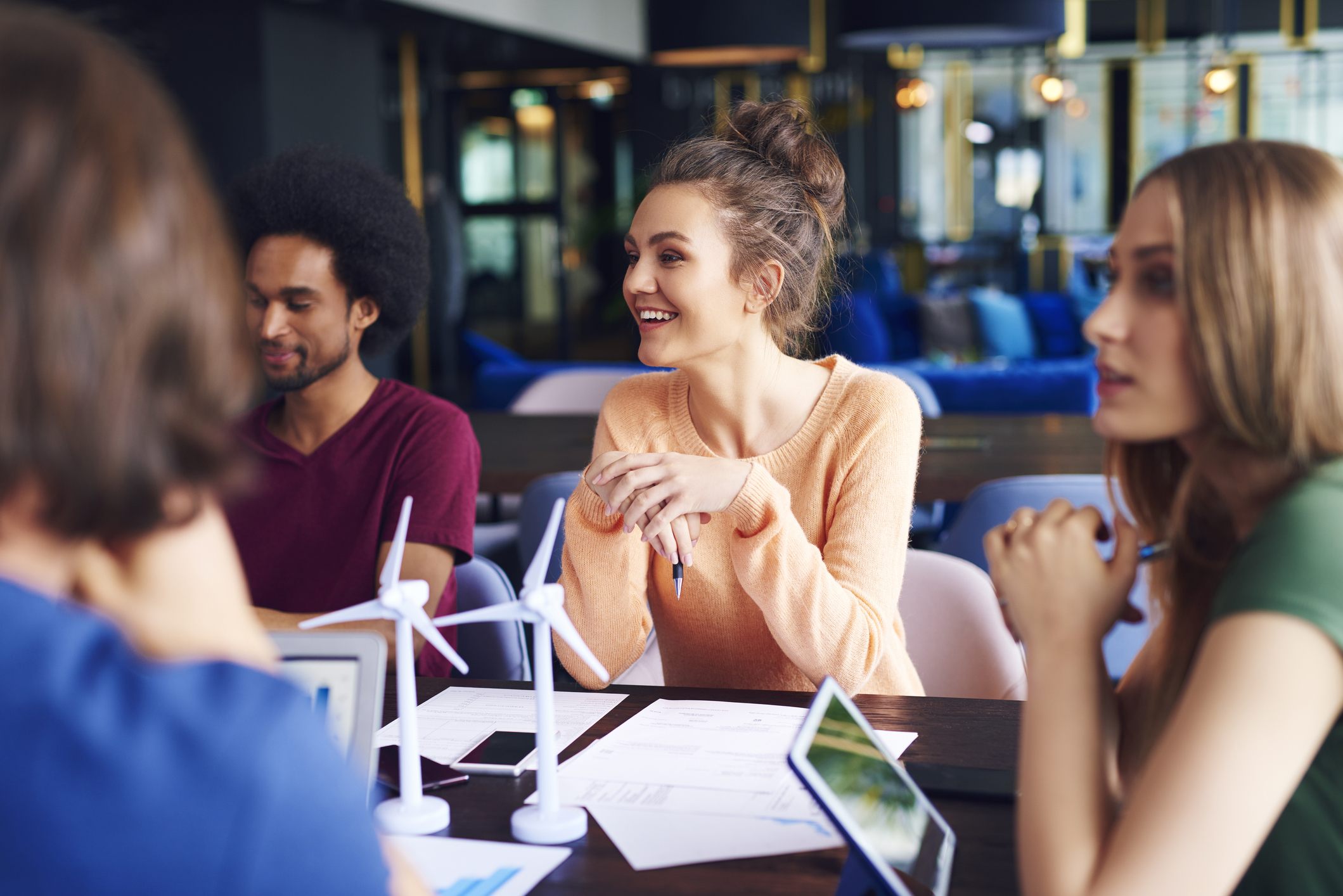 Young coworkers sit at a conference table with model wind turbines on it