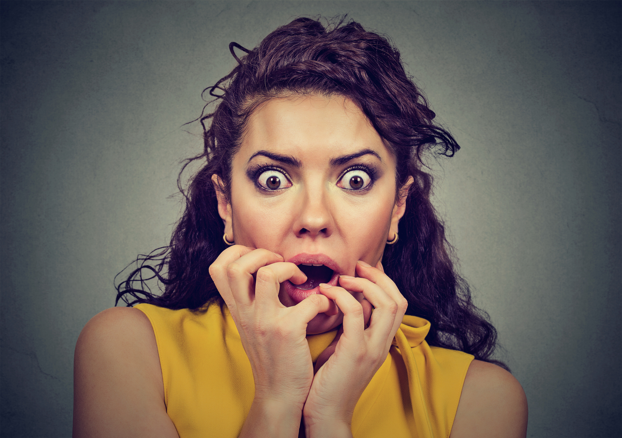 Emotional woman with a frightened look and her hands on her mouth.
