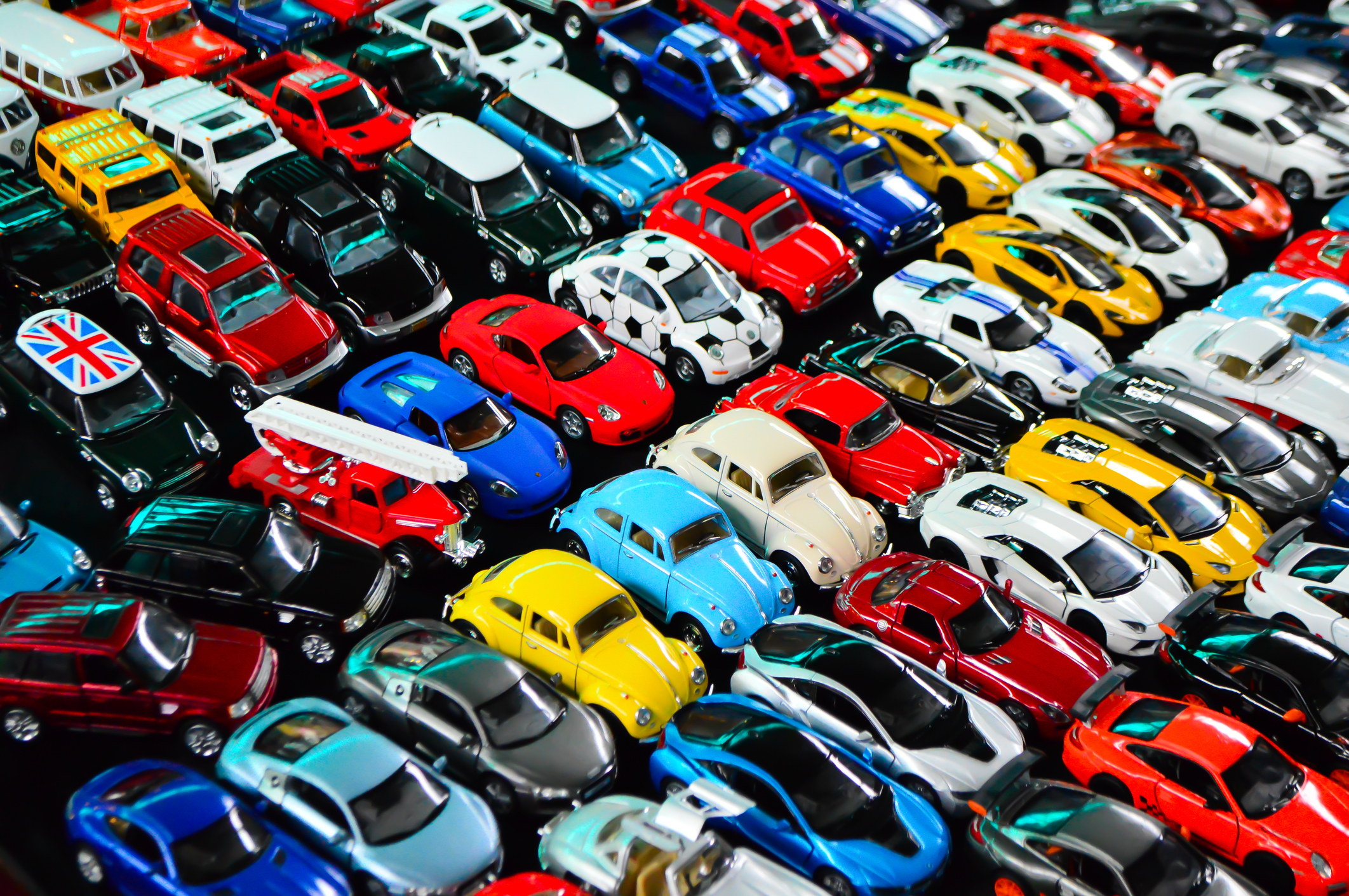 A large collection of toy cars arranged in rows.