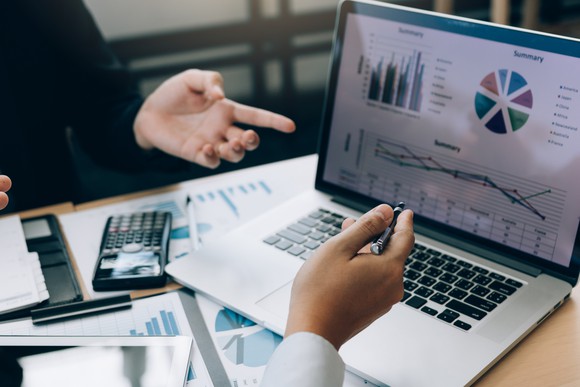Two business associates discussing graphs presented on a laptop.