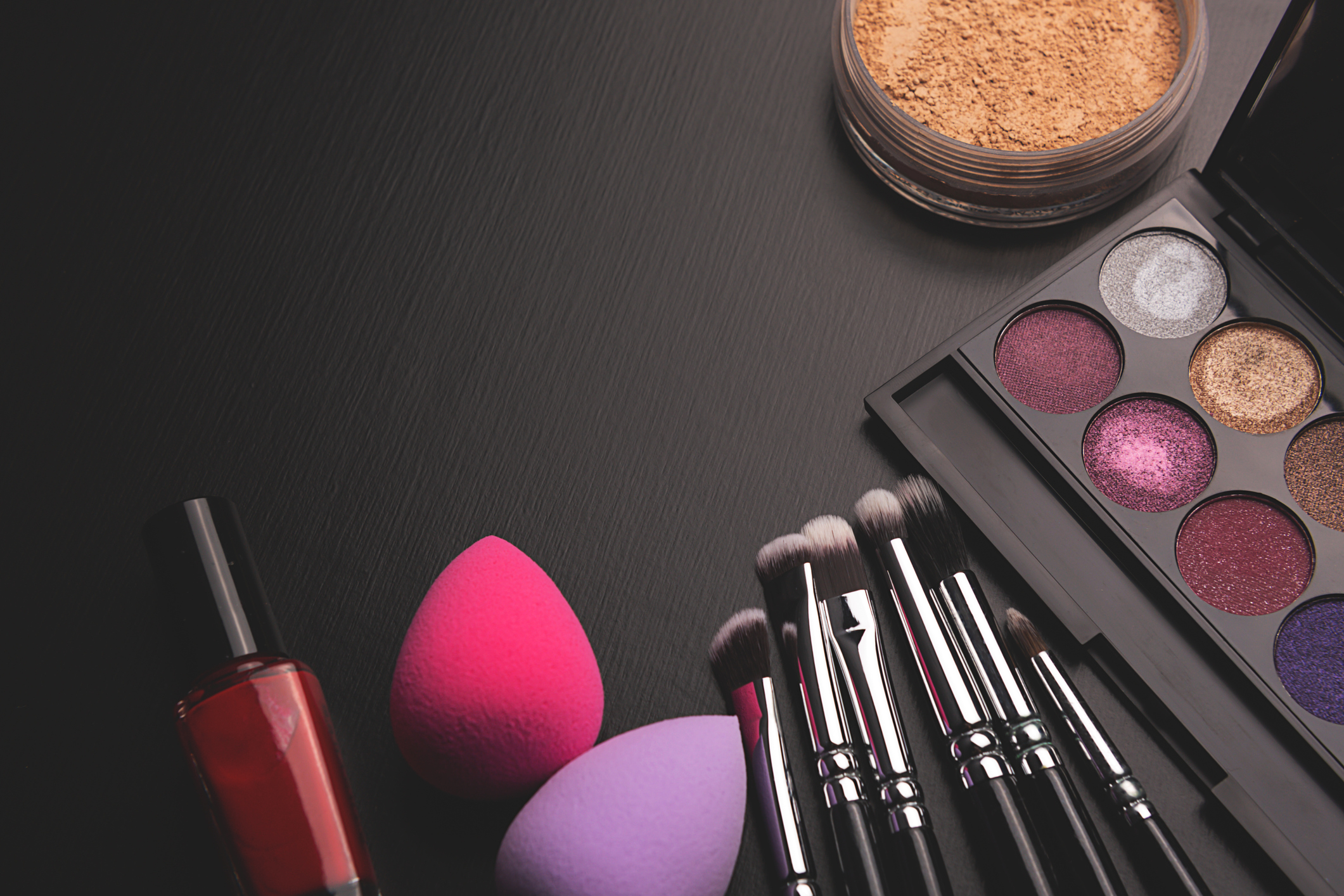 cosmetics and application brushes on a black table