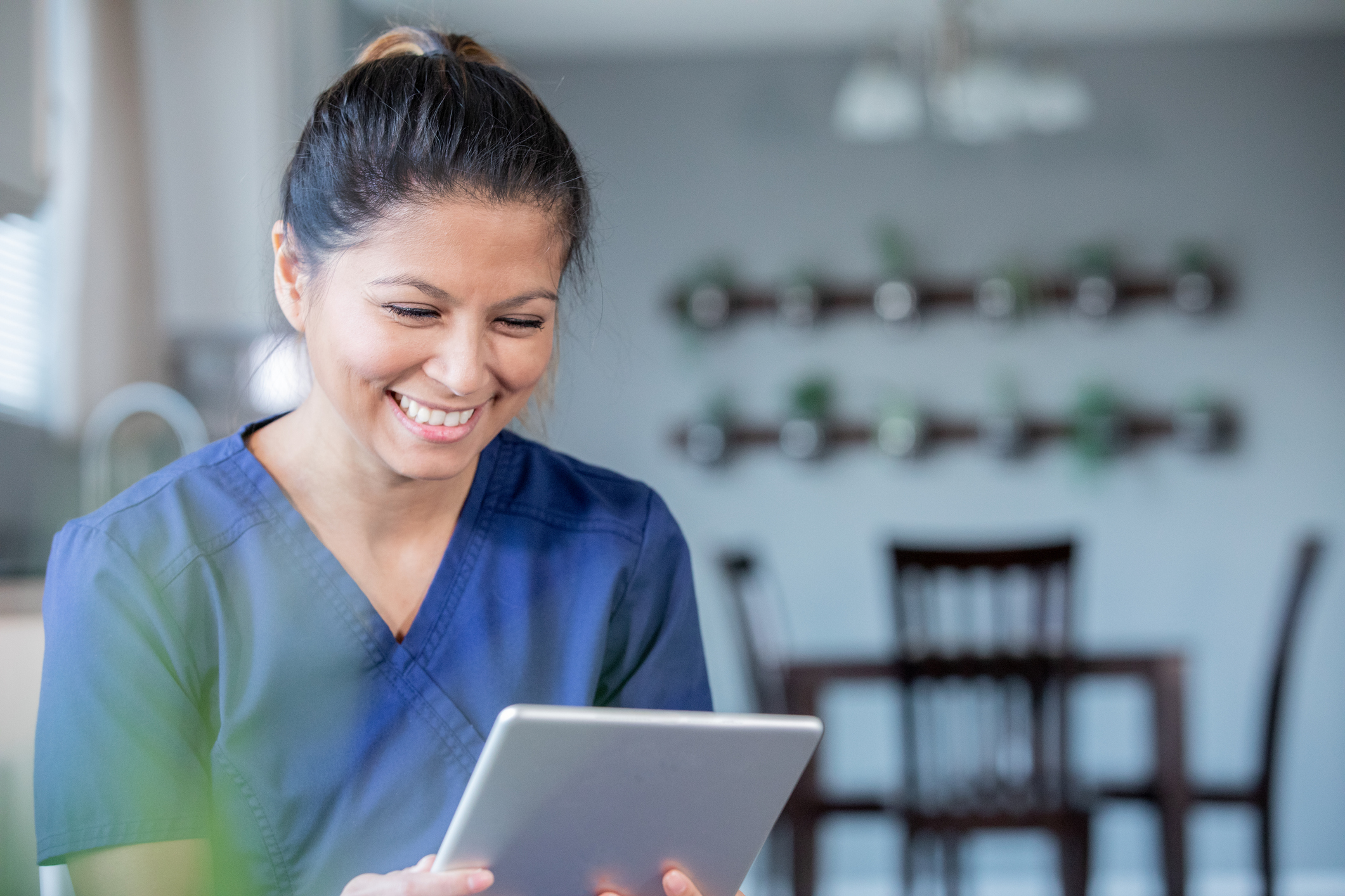 Smiling nurse holding a tablet on a virtual visit with a patient. 