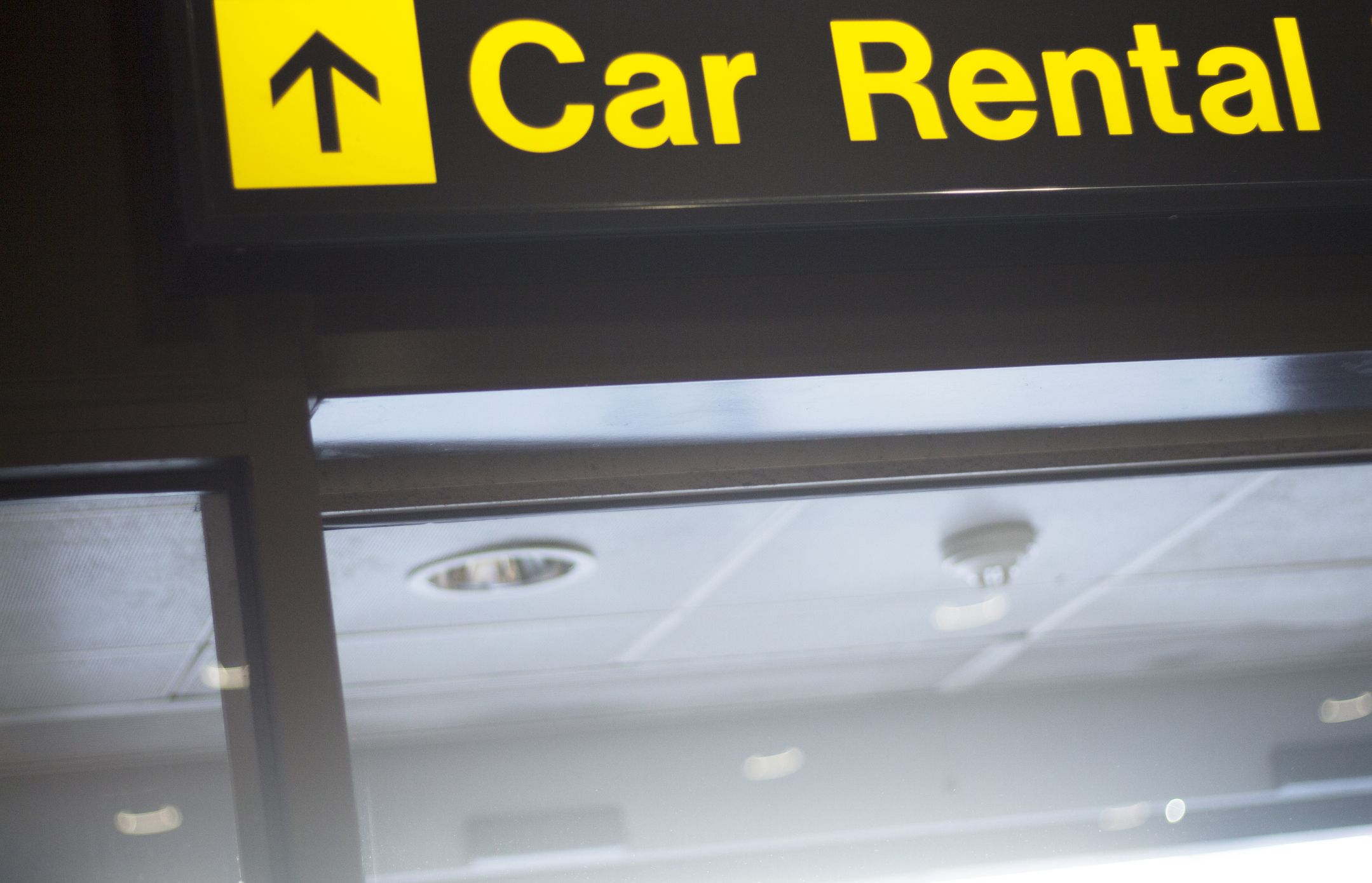A sign in an airport pointing travelers to car rental.