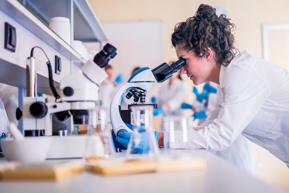 A scientist looking through a microscope.