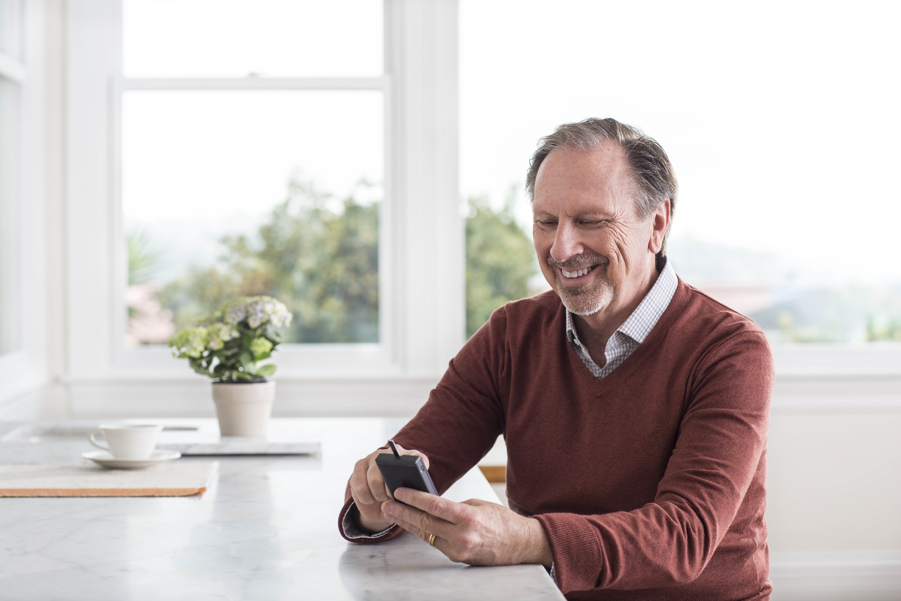 A man smiling while checking his blood sugar on a connected device.