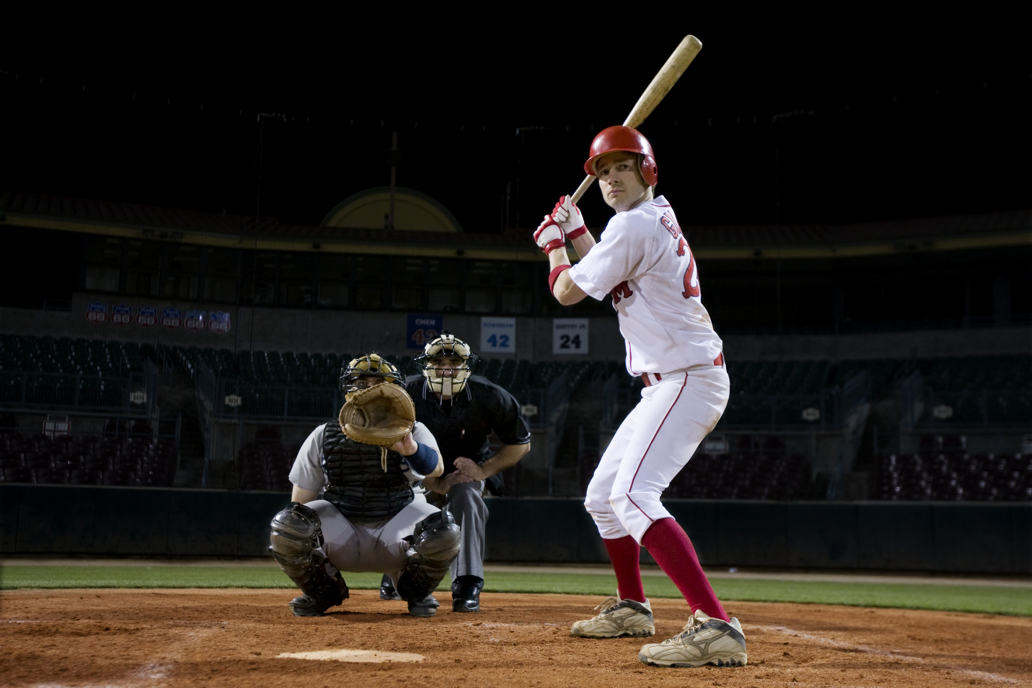 A batter at the plate waiting for the pitch. The catcher has his mitt out and the umpire is behind him.