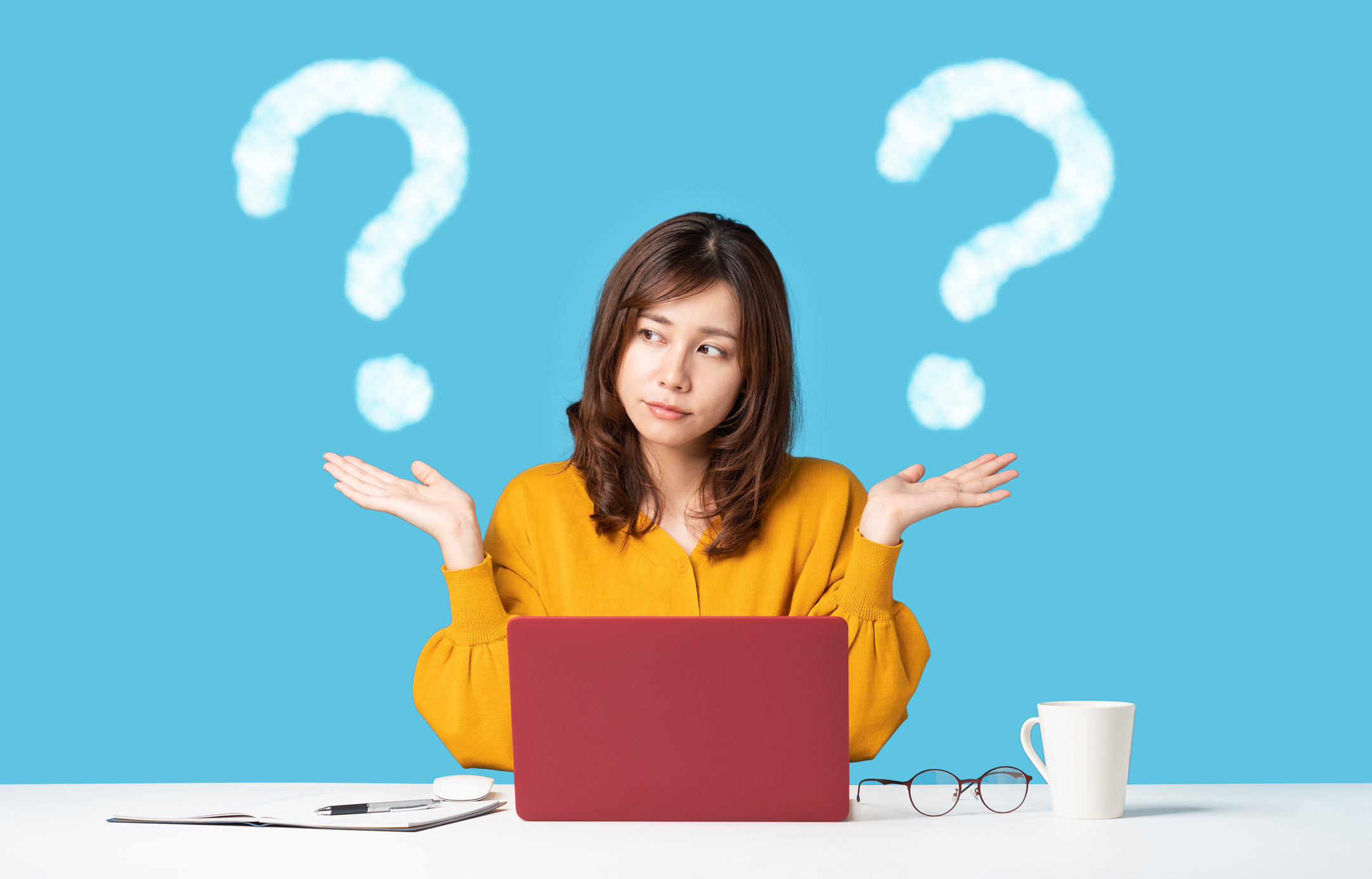 A woman holds up both her hands, with question marks above each.