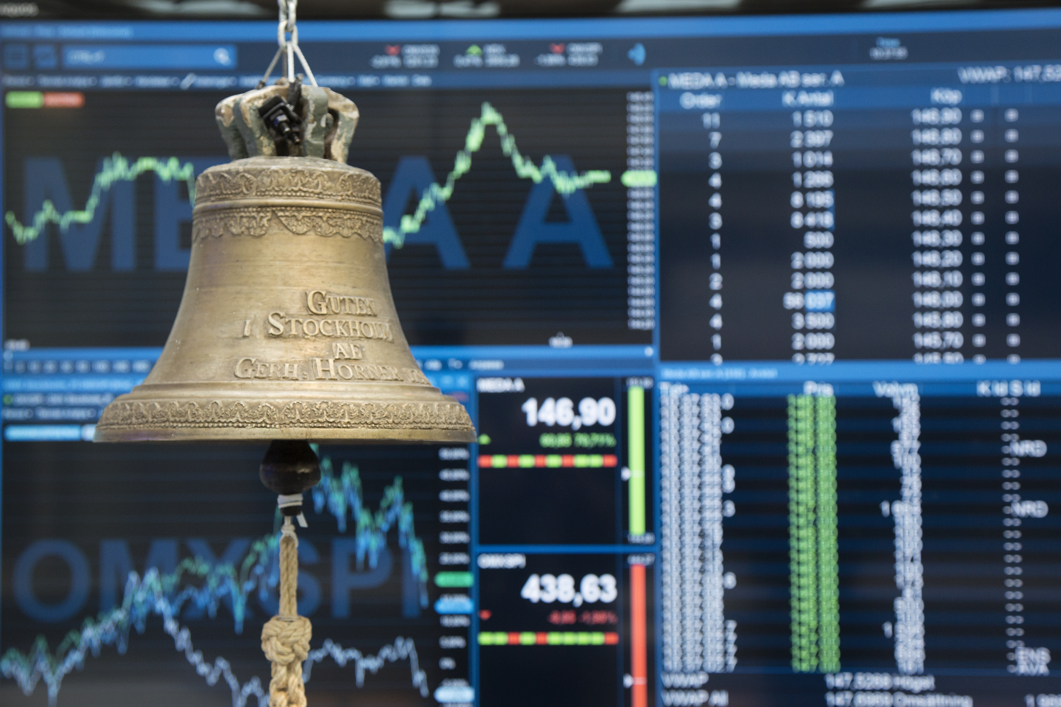 Bell at the Nasdaq with display screens in the background