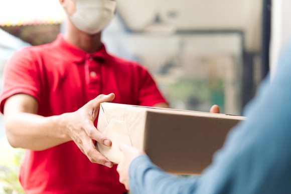 Person in mask handing another person a package