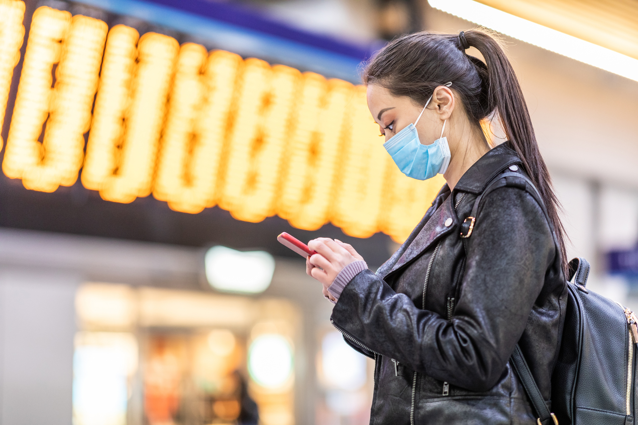Woman in protective mask using a smartphone.