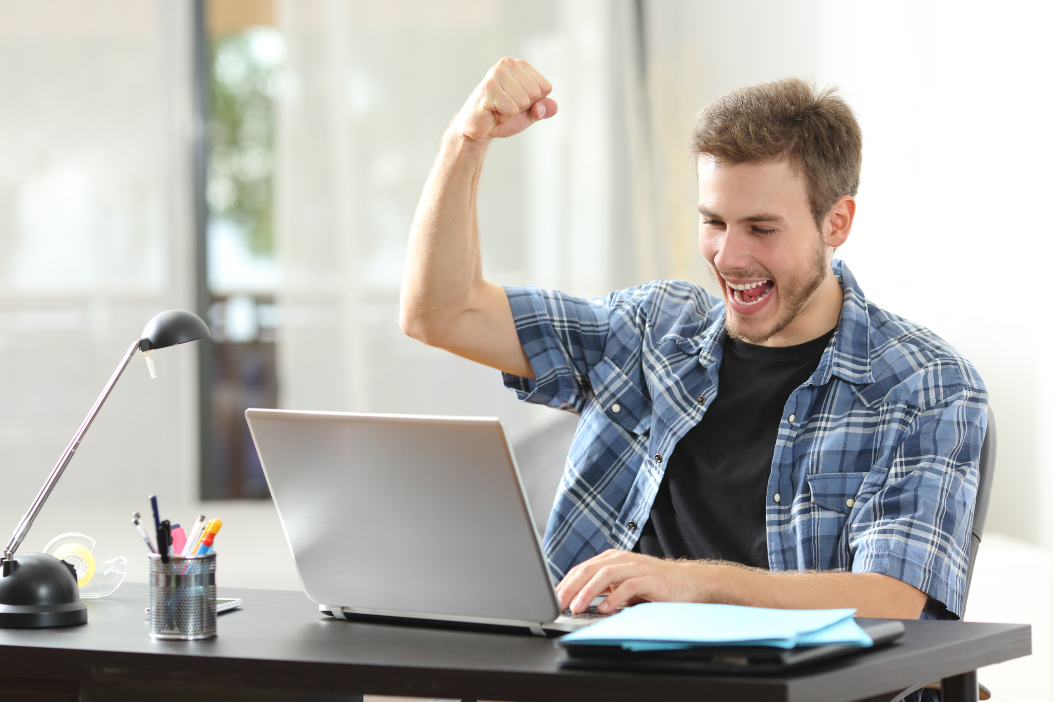 Man looking at laptop and cheering.