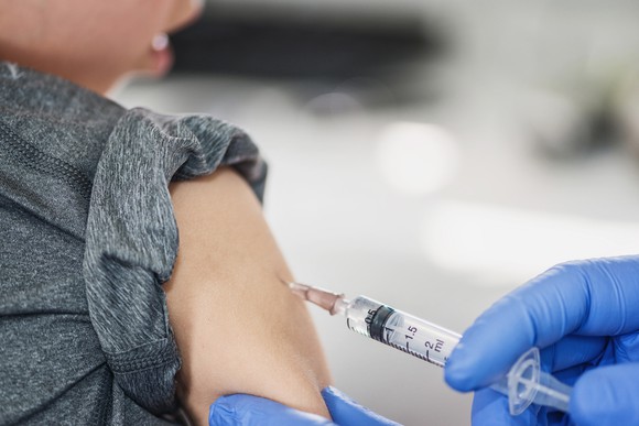 Gloved hands giving an injection into a child's shoulder