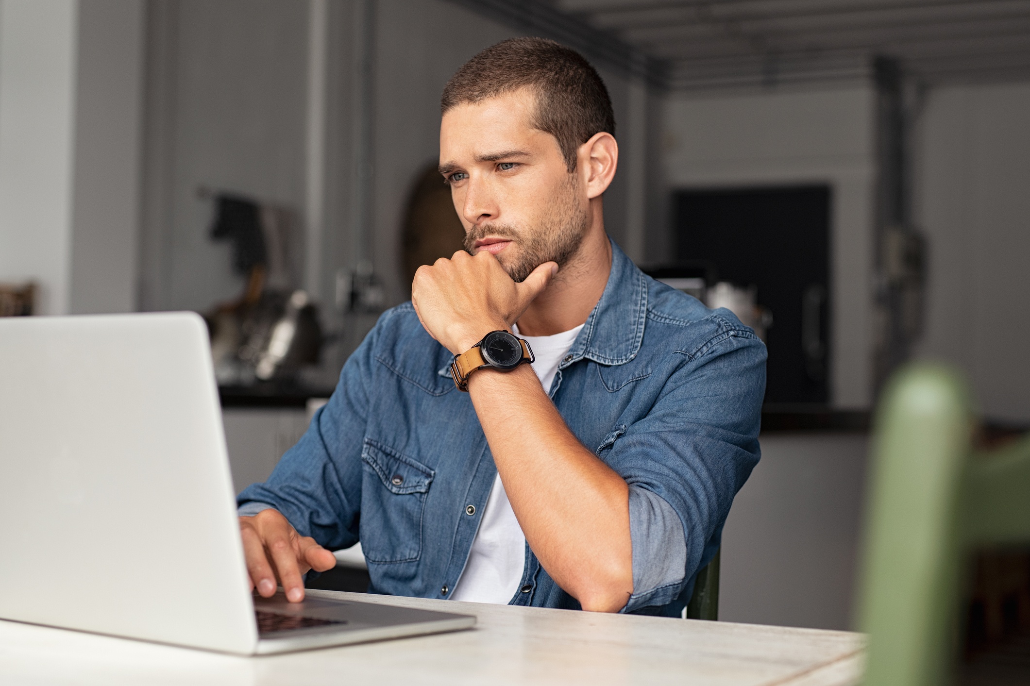 Man with a serious facial expression using a laptop.