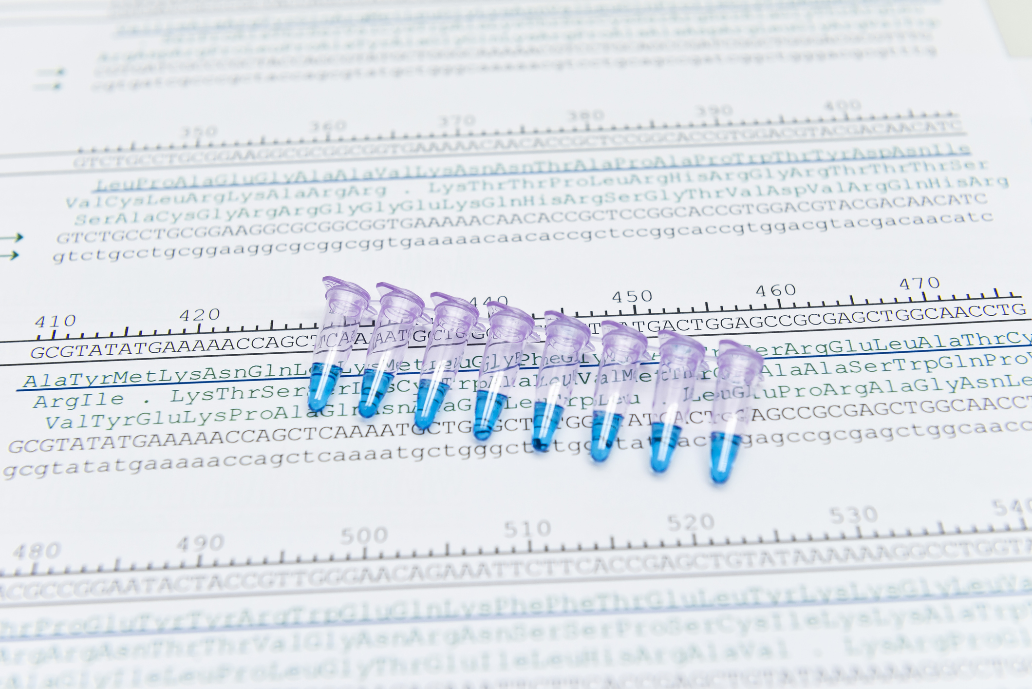 A series of test tubes laid on top of a page with genetic sequences.