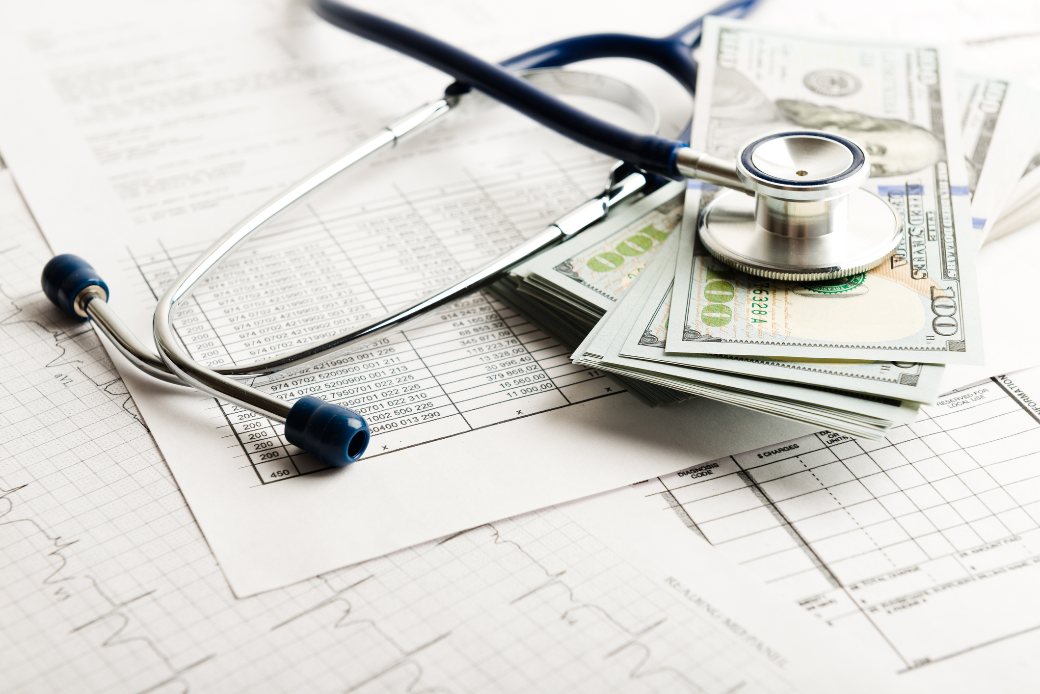 Stack of $100 bills and stethoscope.