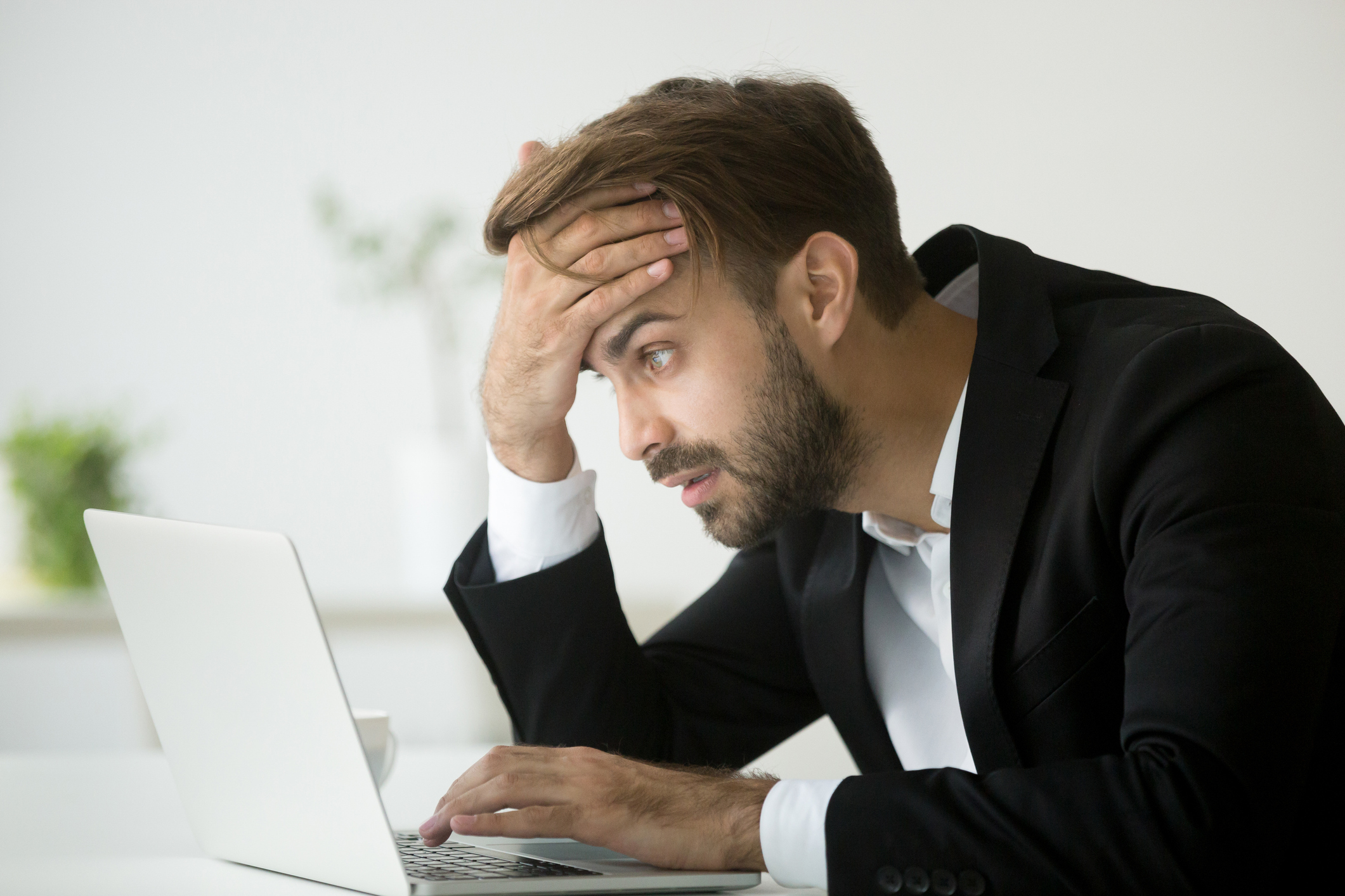 Man at laptop holding his head