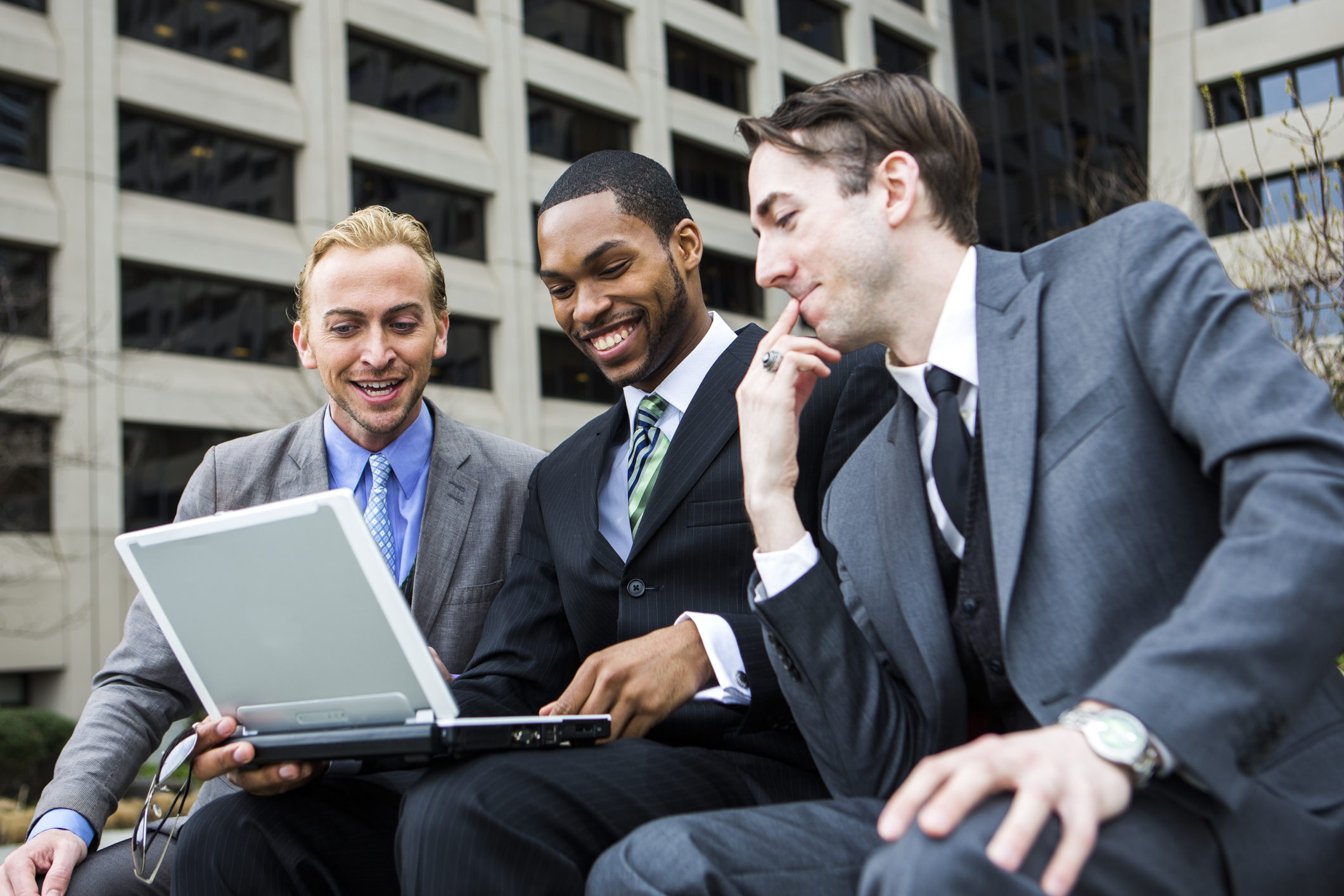 Three friends look at a laptop.