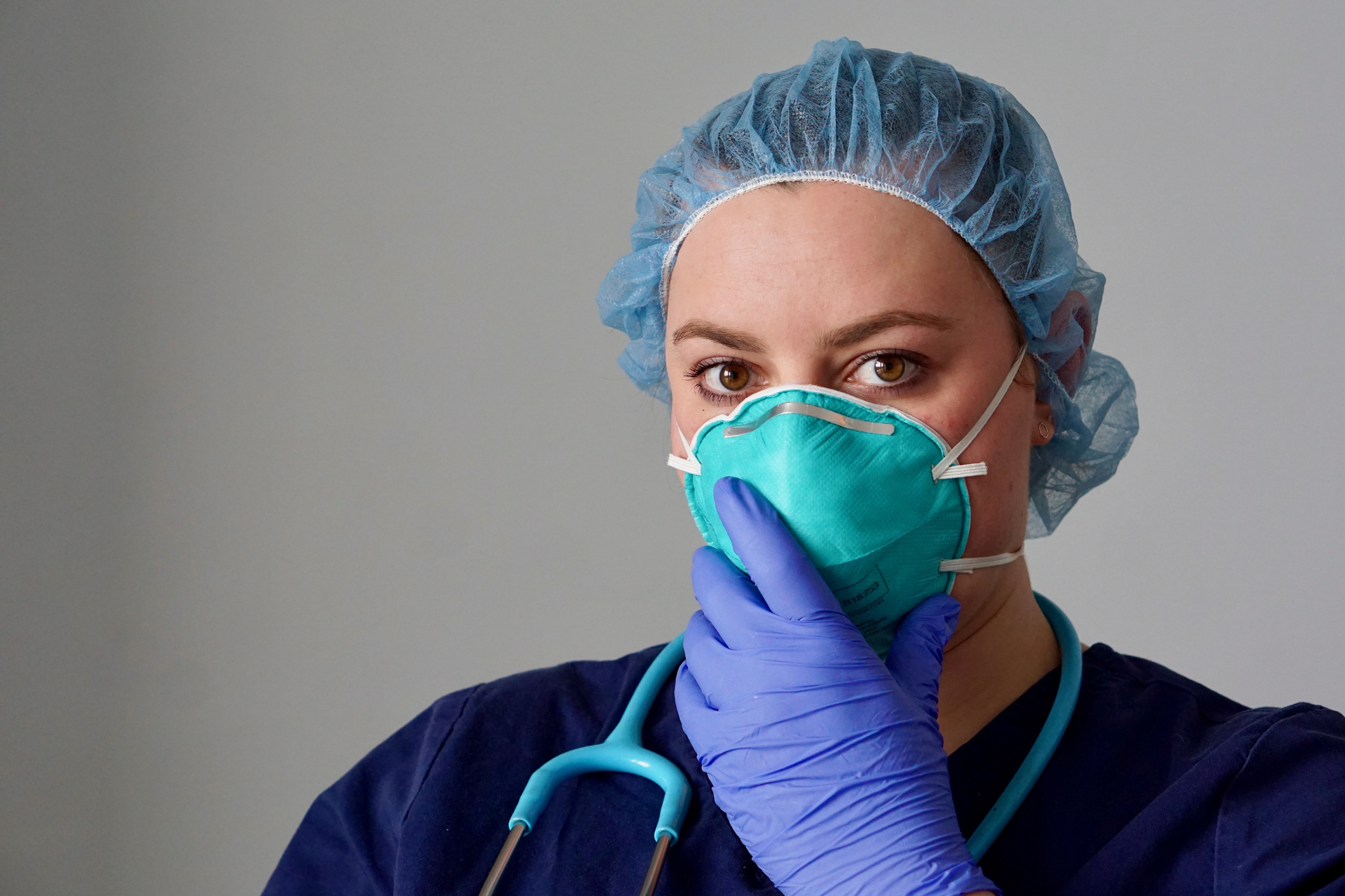Healthcare professional holding gloved hand up to her face mask