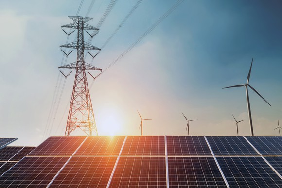 wind and solar power, along with electric transmission lines at sunset